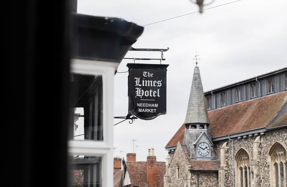 The Limes Hotel sign on High Street, Needham Market, with St John the Baptist church behind