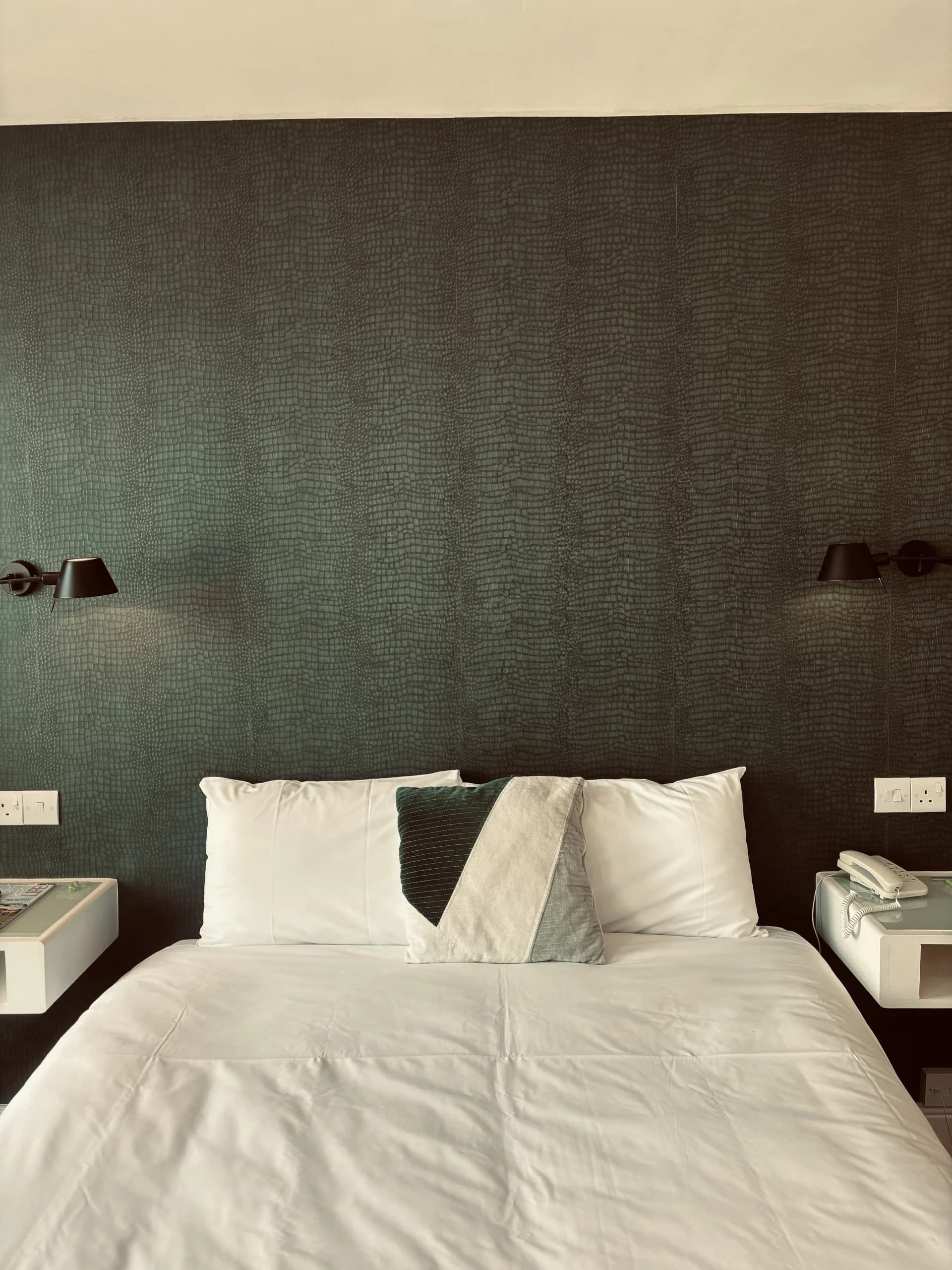 Contemporary bedroom with dark teal wallpaper and crisp white linen at The Limes Hotel