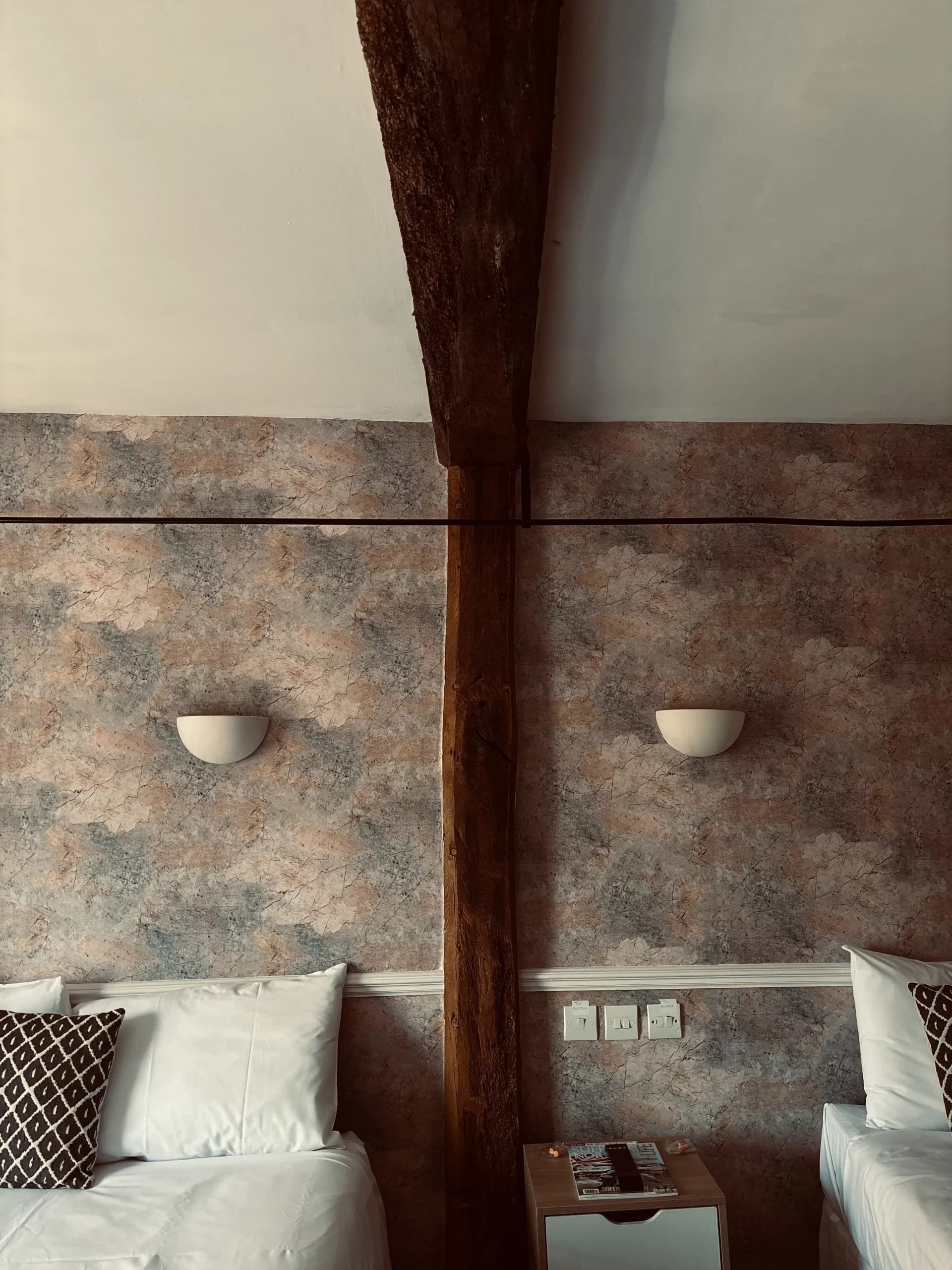 Twin room with exposed wooden ceiling beam and terracotta-effect wallpaper